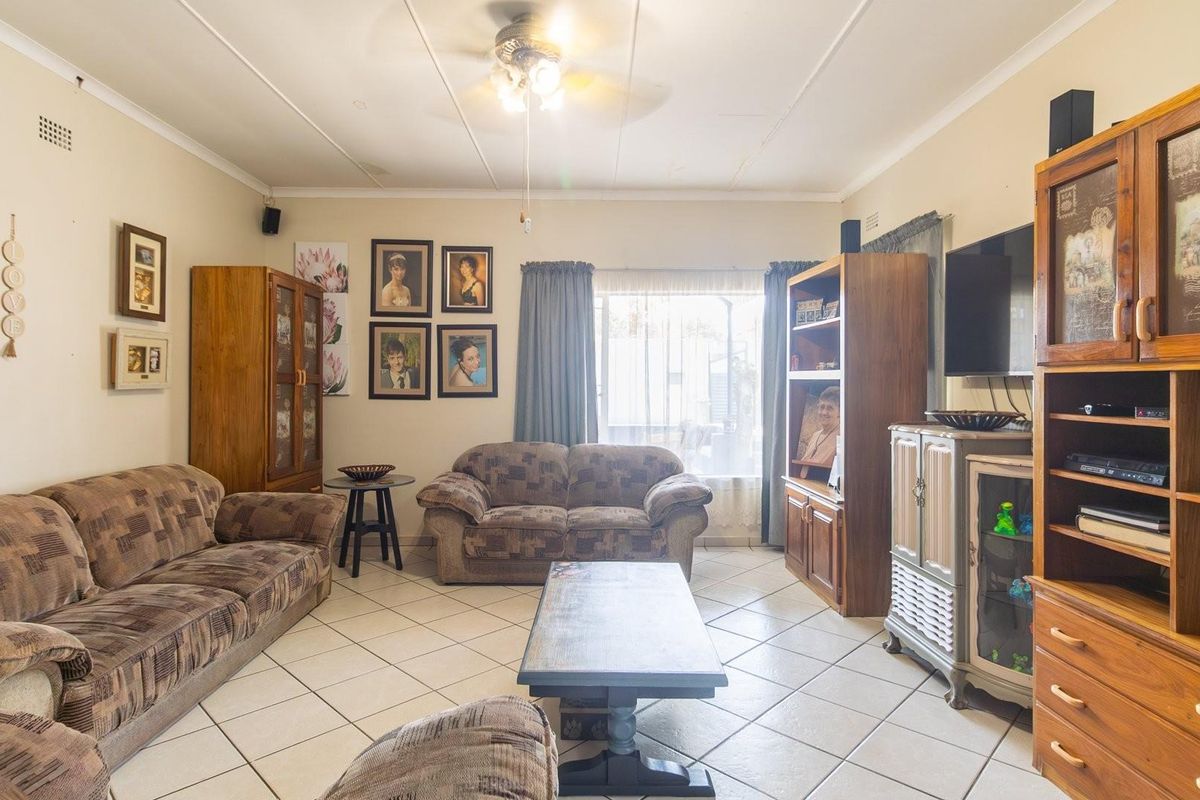 A traditional living room featuring tiled flooring, a ceiling fan, and large windows allowing natural light into the space.