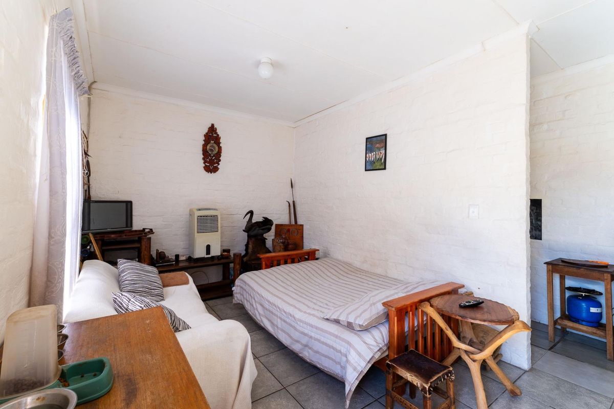A compact bedroom featuring painted brick walls and tiled flooring, offering a simple and functional living space.
