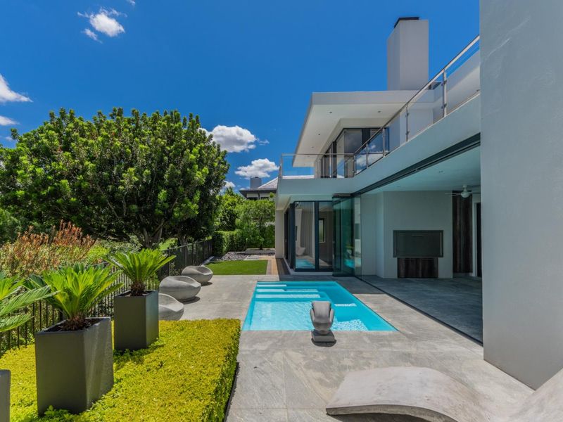 Modern outdoor living area featuring a sleek swimming pool, tiled patio, and seamless indoor-outdoor flow through large sliding glass doors.