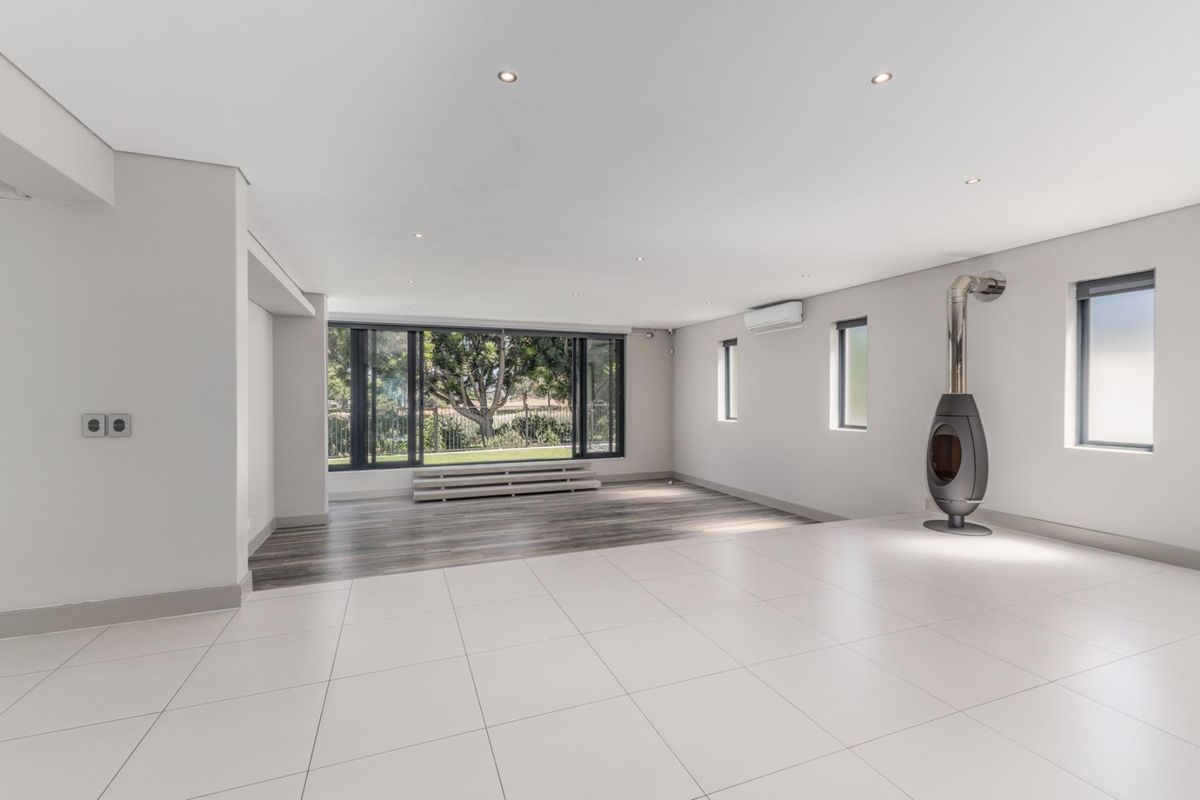 Spacious, modern open-plan living area featuring a sleek freestanding fireplace, recessed lighting, split-system air conditioning, and a mix of tiled and laminate flooring.