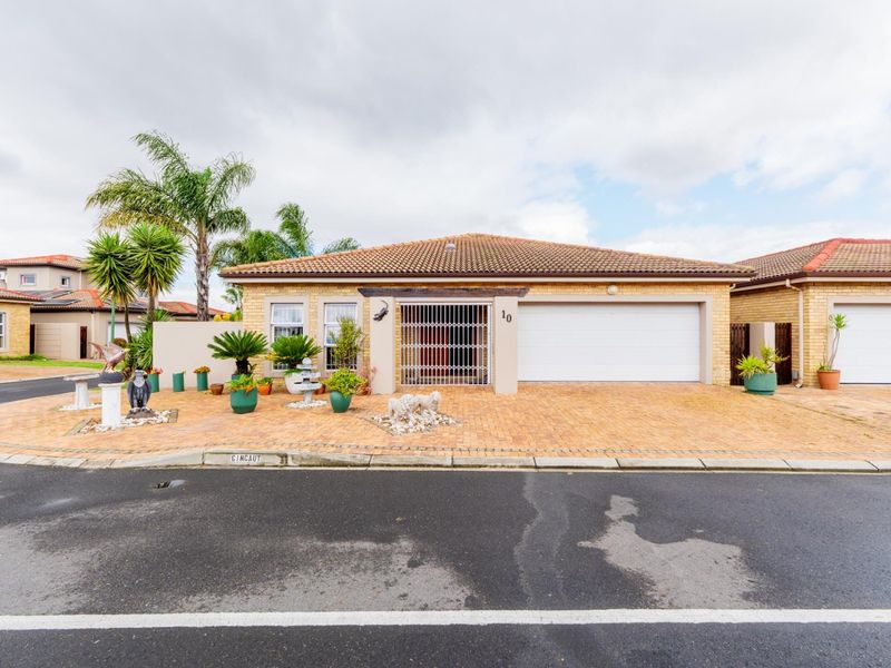 Front elevation of a single-story brick house featuring a paved driveway, double garage, and secure gated entrance.