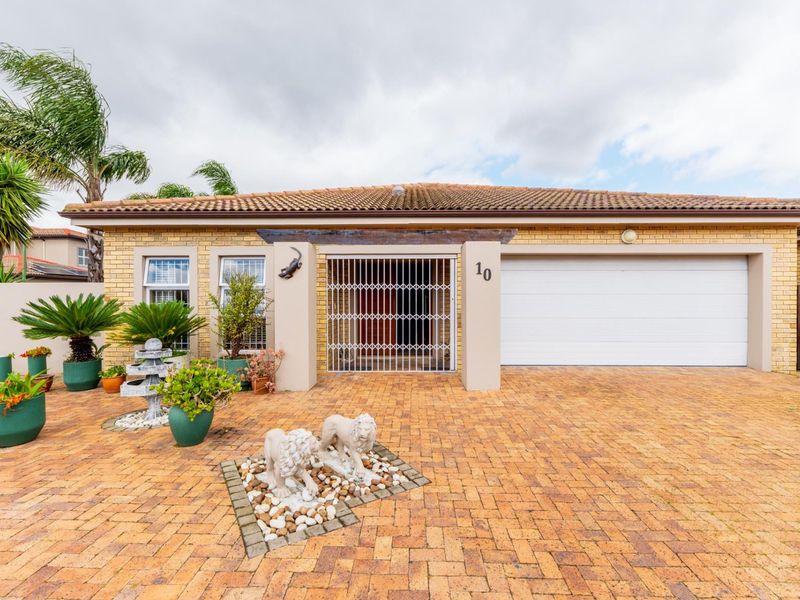 Front elevation of a single-story brick home featuring a paved driveway, integrated garage, and secure entrance gate.