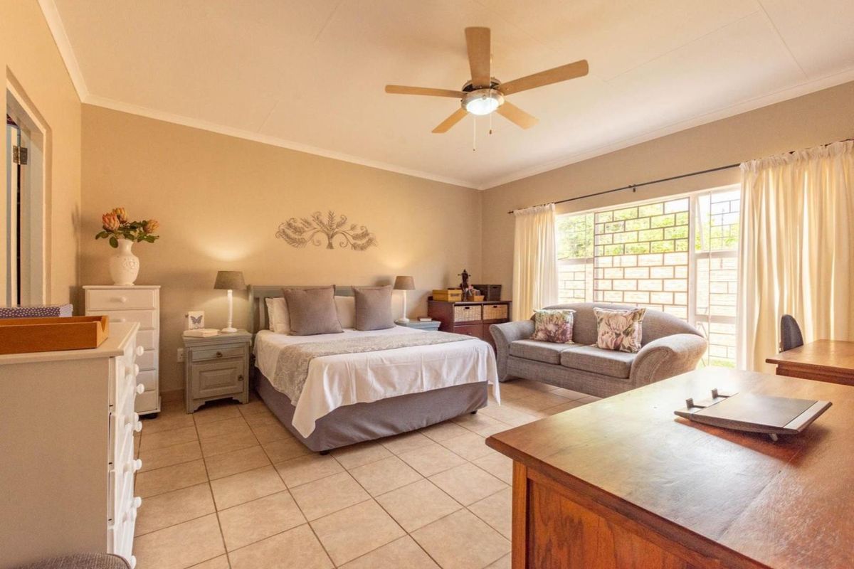 Spacious bedroom featuring tiled flooring, a ceiling fan, and large windows that provide ample natural light.