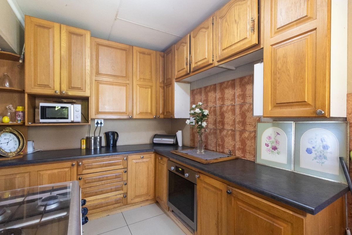A functional kitchen featuring traditional oak-style cabinetry, dark laminate countertops, a built-in oven, and a tiled backsplash.