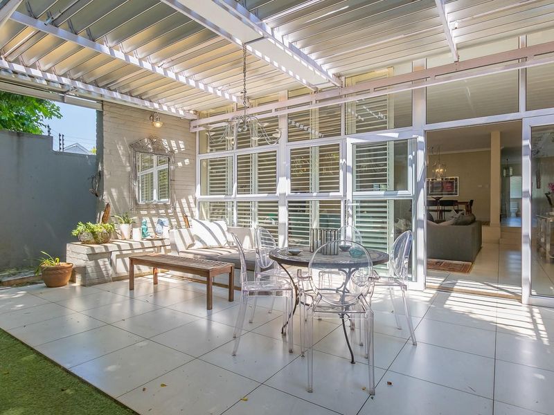 A covered patio featuring a louvre roof, tiled flooring, and large aluminium sliding doors providing seamless access to the interior living space.