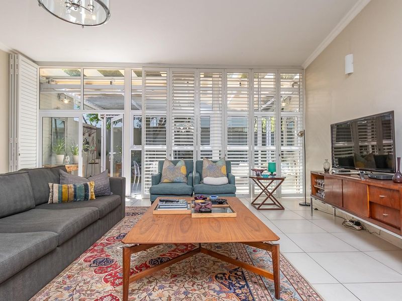 A bright and spacious living room featuring large glass sliding doors with white plantation shutters, leading out to a covered patio area.