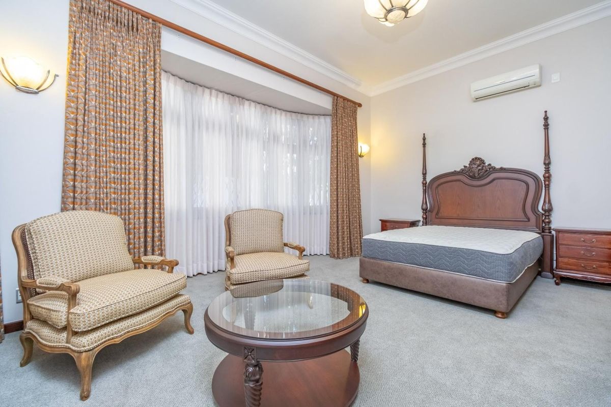 Spacious bedroom featuring a large bay window, wall-mounted air conditioning unit, and crown molding detail.