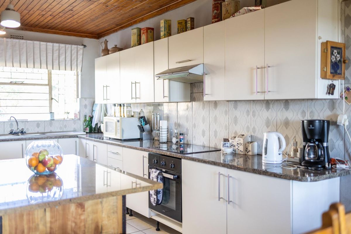 A functional kitchen featuring white cabinetry, granite countertops, a built-in oven with extractor fan, and a wooden ceiling finish.
