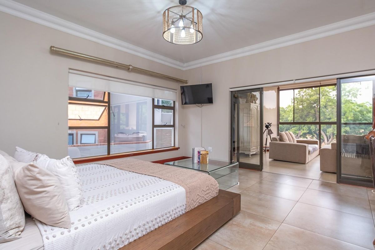 Spacious bedroom featuring large windows, tiled flooring, and sliding glass doors leading to an adjoining sunroom or balcony area.