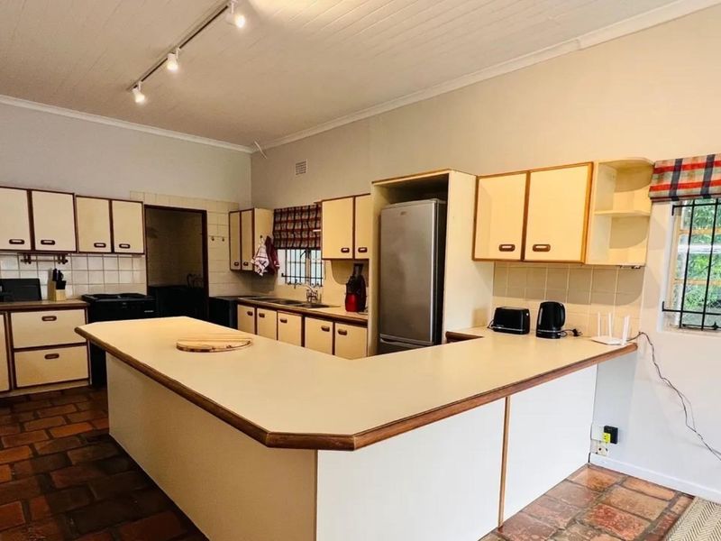 A functional kitchen featuring U-shaped cabinetry, laminate countertops, terracotta flooring, and track lighting, offering a classic layout with potential for modern updates.