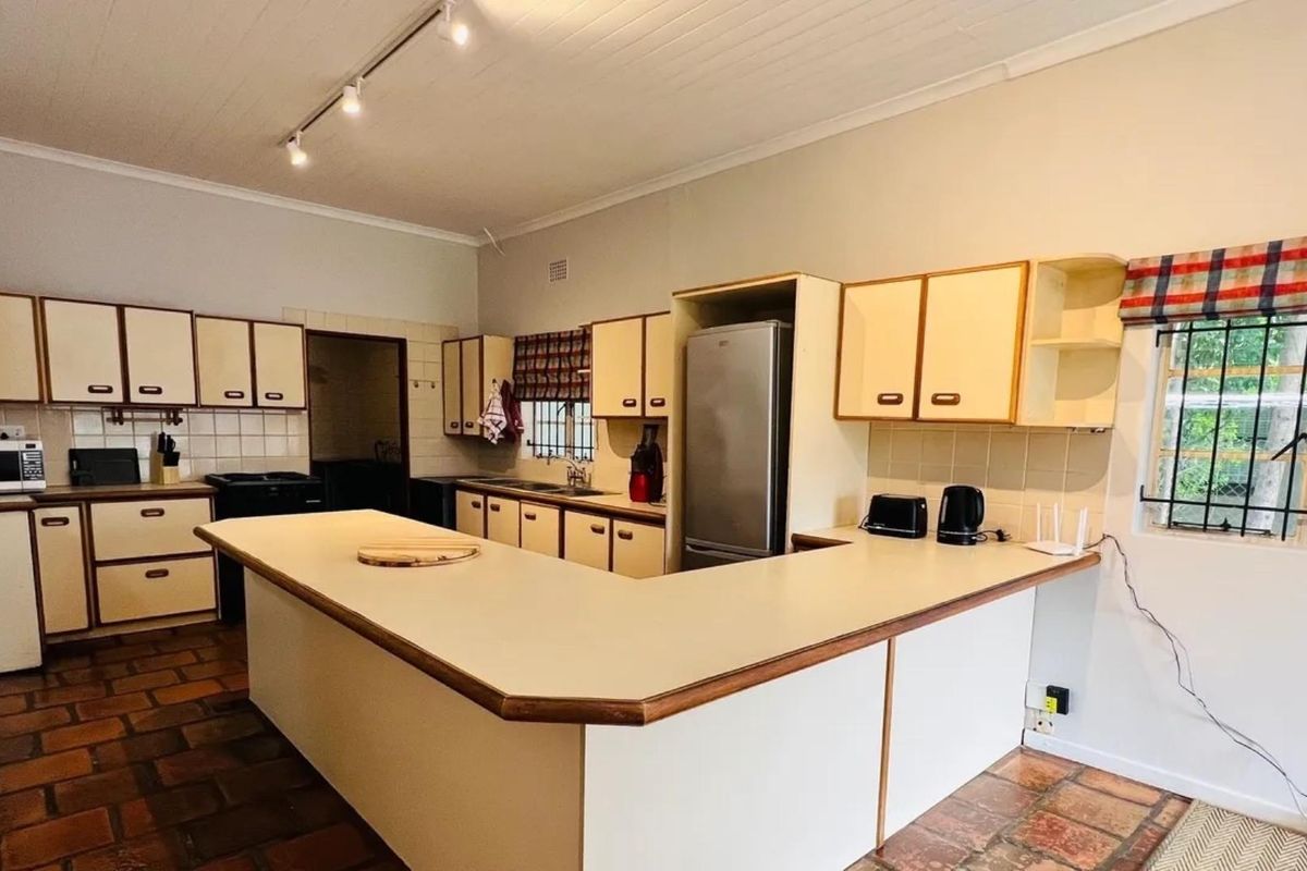 A functional kitchen featuring U-shaped cabinetry, laminate countertops, terracotta flooring, and track lighting, offering a classic layout with potential for modern updates.