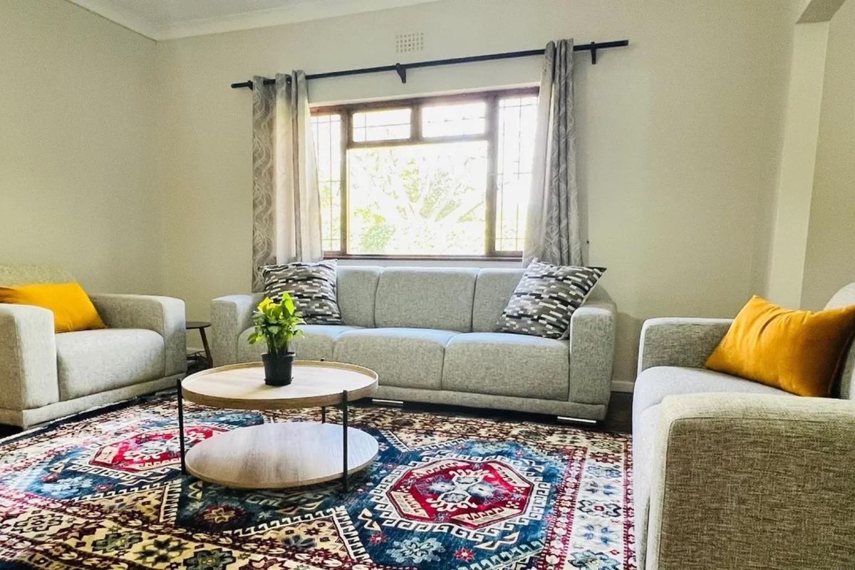 A comfortable living room featuring a large window with security bars and neutral wall finishes, providing a bright and inviting space.