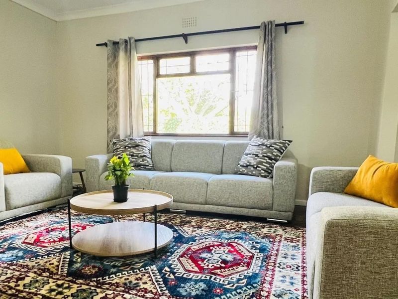A comfortable living room featuring a large window with security bars and neutral wall finishes, providing a bright and inviting space.