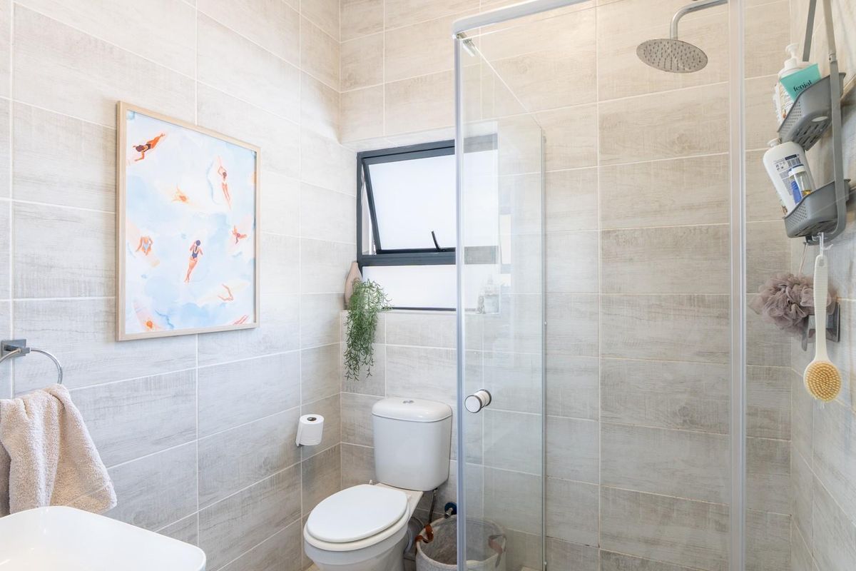 Modern bathroom featuring floor-to-ceiling wood-look tiling, a glass-enclosed shower with a rainfall showerhead, and a contemporary toilet.