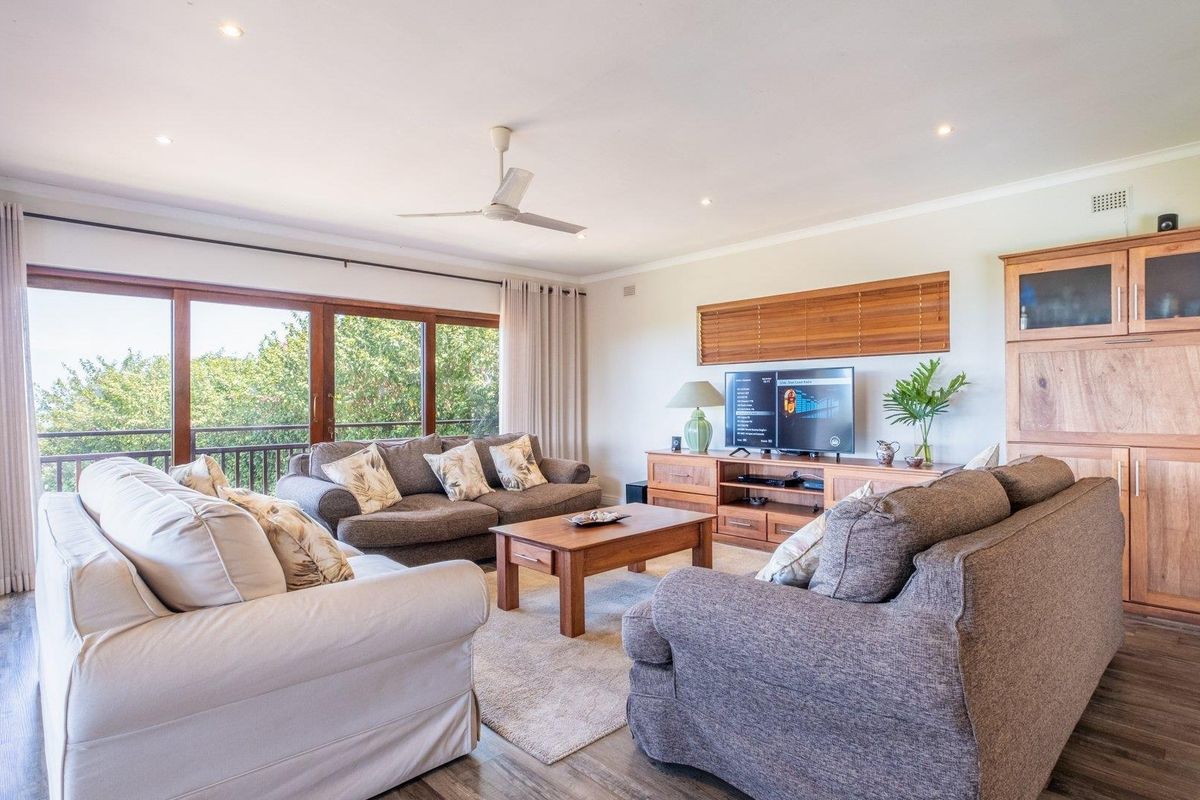 Spacious living room featuring large sliding glass doors, recessed ceiling lighting, a ceiling fan, and wood-look flooring with access to an outdoor balcony.
