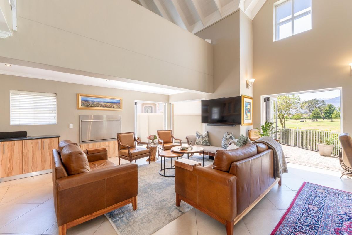 Spacious living area with high vaulted ceilings, built-in cabinetry, fireplace, and large glass doors opening to a scenic outdoor patio.