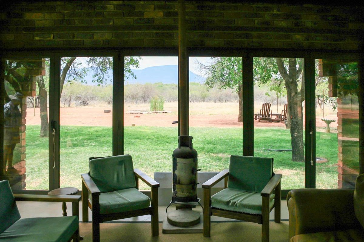 A living area featuring a central freestanding fireplace and large glass sliding doors that provide expansive views of the surrounding farm landscape.