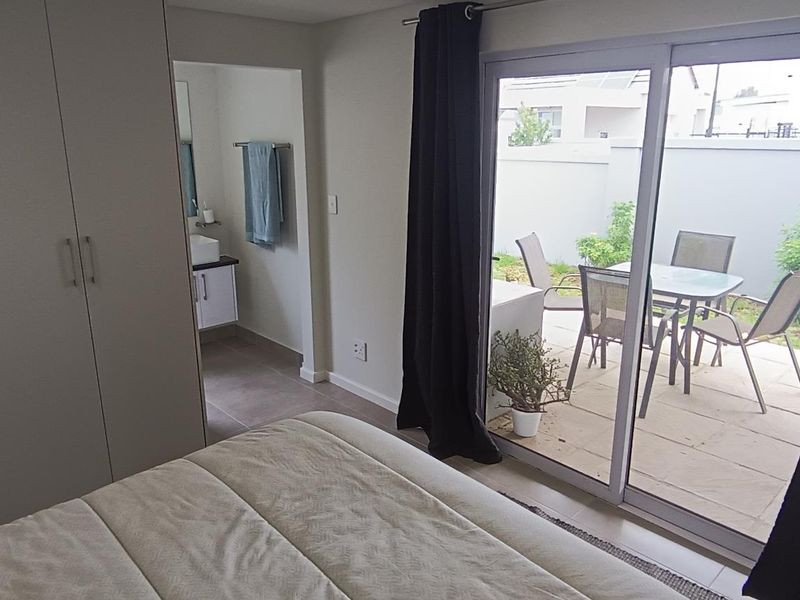 A well-lit bedroom featuring built-in cupboards, tiled flooring, and a sliding glass door providing direct access to a private patio area.