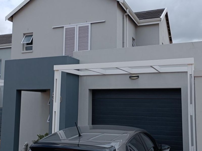 Front elevation of a modern two-story house featuring a garage, pergola, and neutral grey exterior finishes.