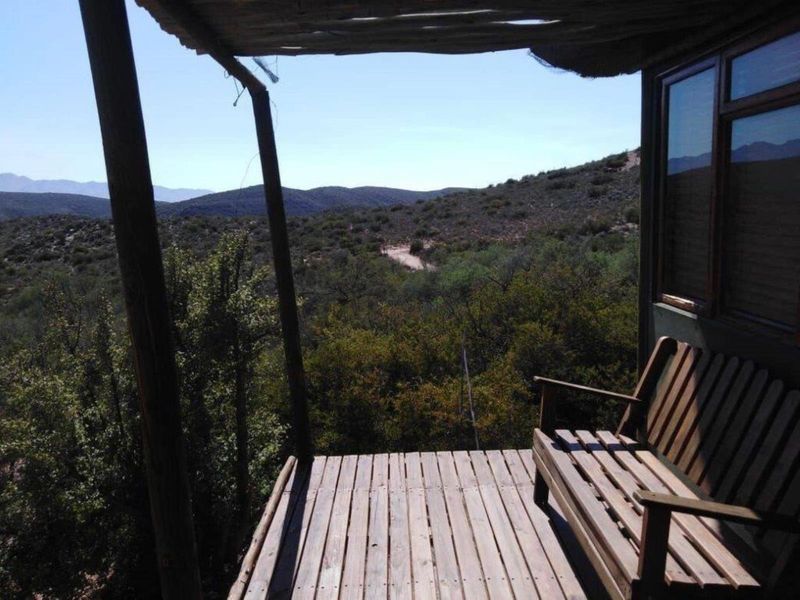 A rustic wooden deck patio offering expansive views of the surrounding natural landscape, featuring a simple timber structure and weathered decking.