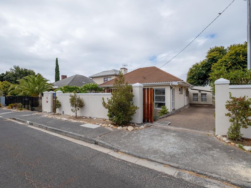 Front exterior view of the property featuring a paved driveway, perimeter wall, and secure gated entrance.