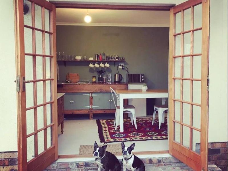 A cozy kitchen area featuring wooden French doors opening to the exterior, built-in cabinetry, and open shelving.