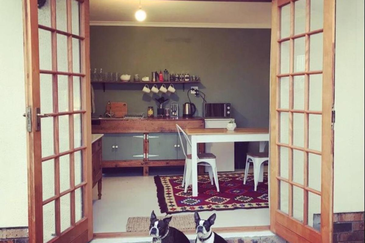 A cozy kitchen area featuring wooden French doors opening to the exterior, built-in cabinetry, and open shelving.