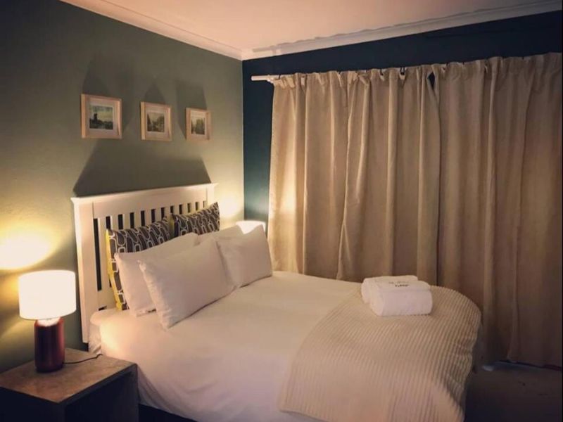 A cozy bedroom featuring dark accent walls, coving, and floor-to-ceiling curtains.