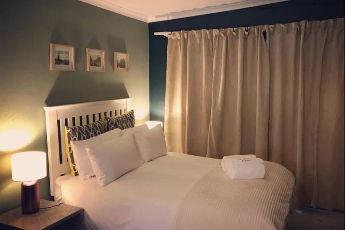 A cozy bedroom featuring dark accent walls, coving, and floor-to-ceiling curtains.