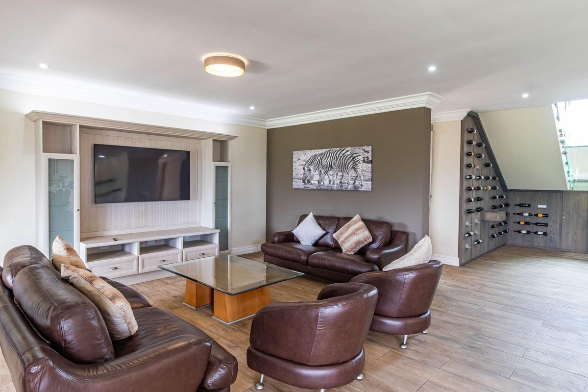 Spacious living room featuring a custom built-in media unit, integrated wine storage, and a staircase with glass balustrades.