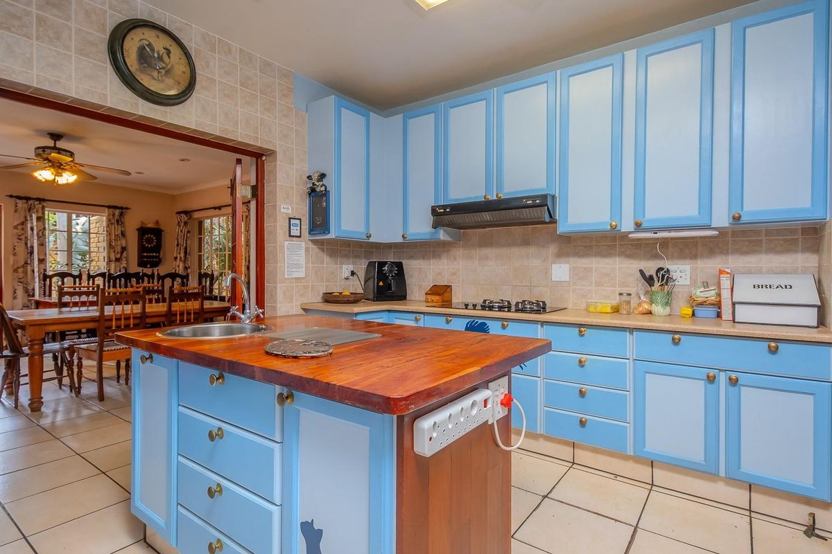 A functional kitchen featuring blue cabinetry, a wooden island countertop, tiled flooring, and a built-in gas hob with an extractor fan.
