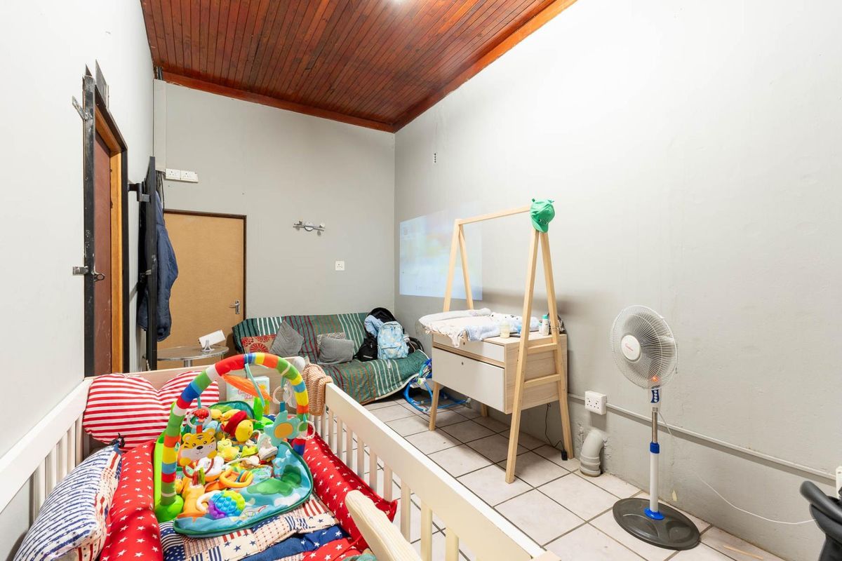 A functional room featuring tiled flooring and a timber-clad ceiling, currently utilized as a nursery space with basic electrical fixtures.
