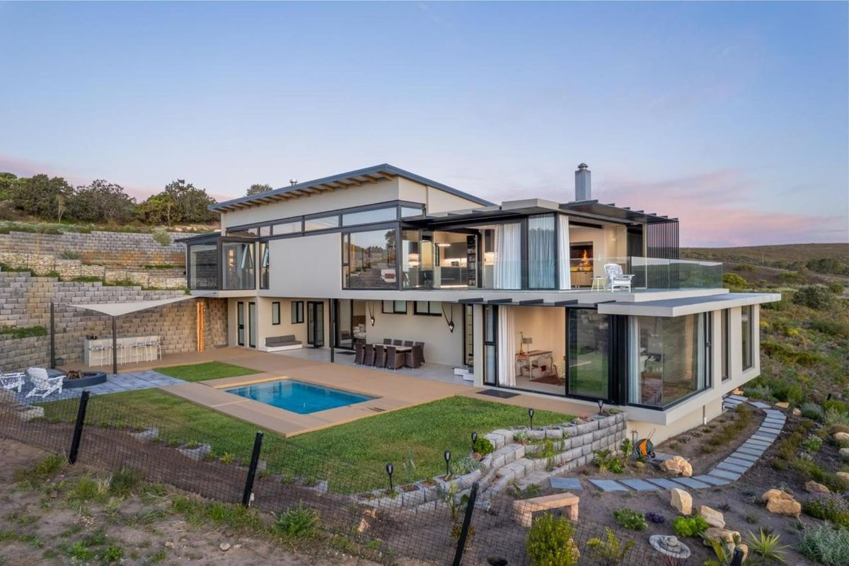 Modern multi-level residence featuring expansive glass facades, a swimming pool, landscaped garden, and integrated outdoor entertainment areas with scenic views.