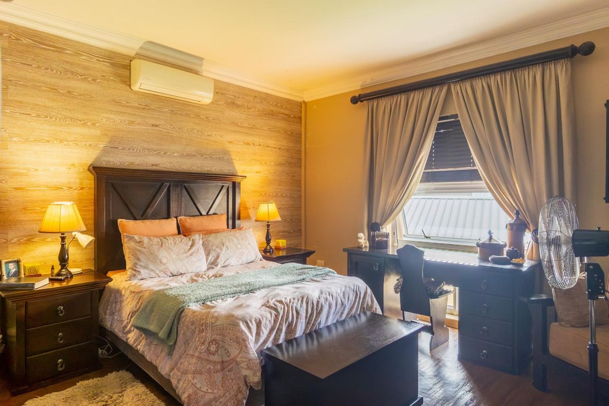 A cozy bedroom featuring wood-look accent wall paneling, crown molding, and a wall-mounted air conditioning unit.