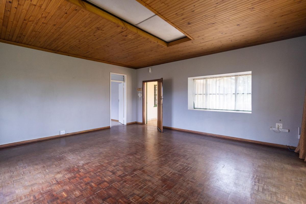 Spacious living area featuring traditional parquet flooring and a timber-clad ceiling with a central recessed light panel.