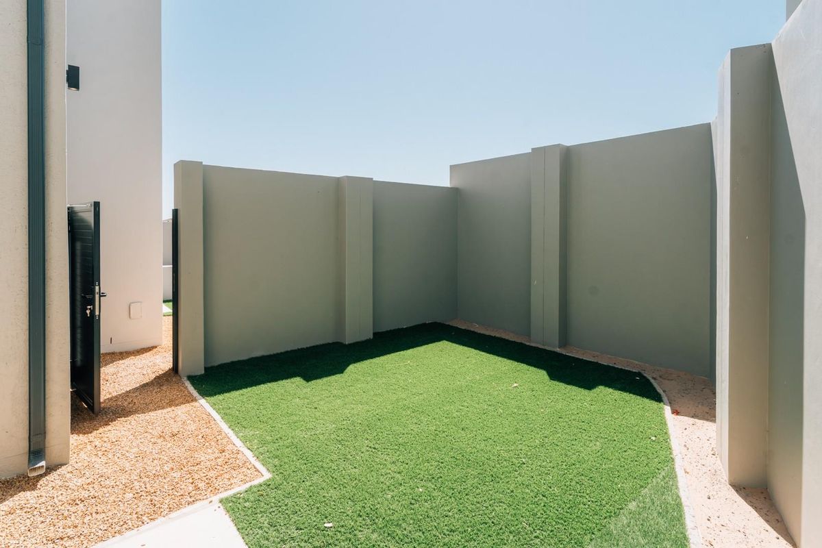 A private, low-maintenance rear garden area featuring artificial turf, gravel borders, and high perimeter boundary walls for added privacy.