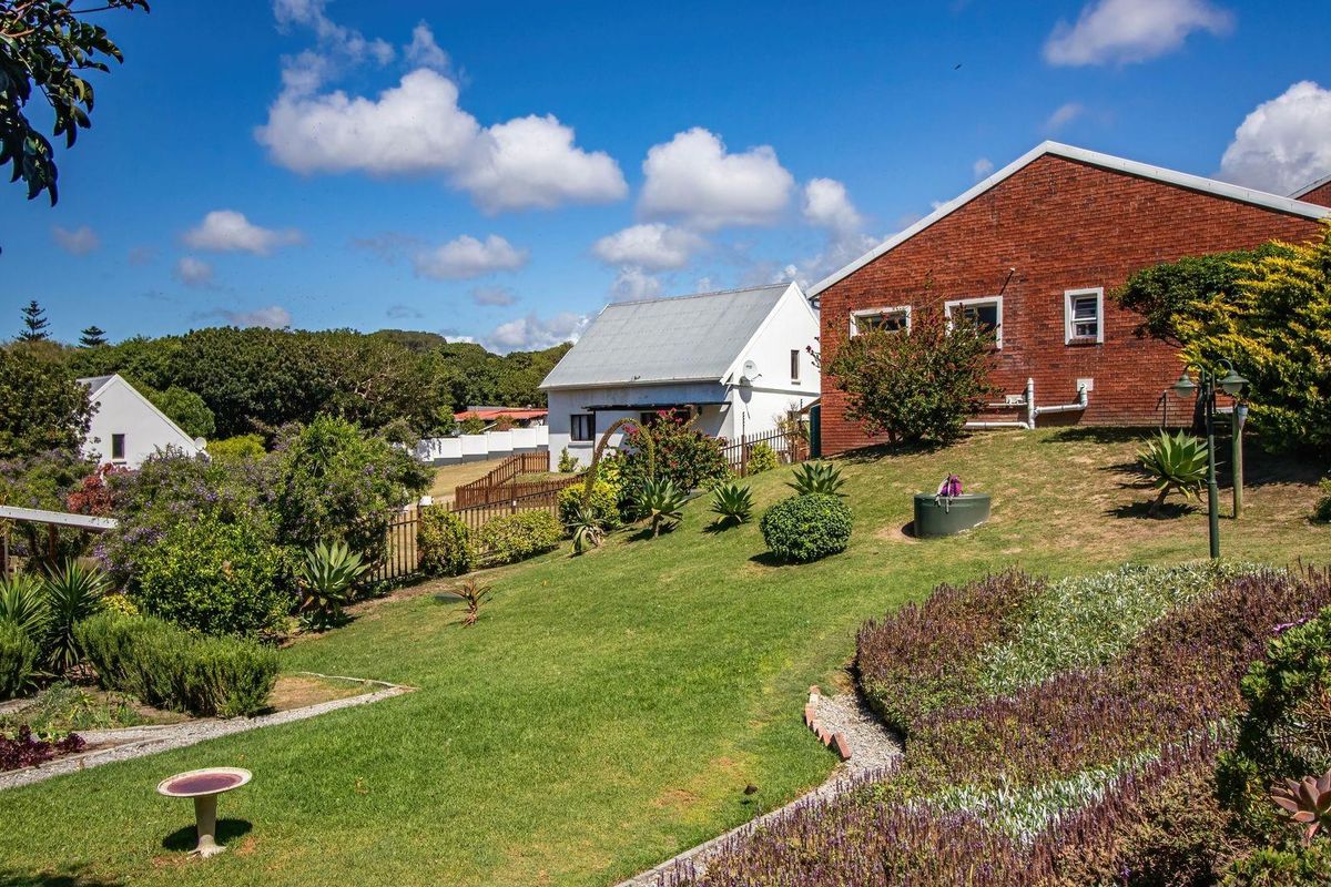 A view of the rear garden area featuring established landscaping, lawn, and the rear elevation of the residential building.