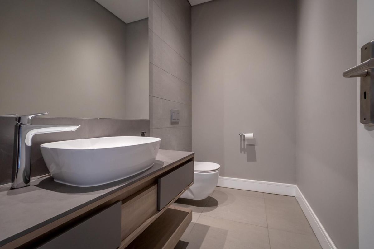 Modern guest bathroom featuring a sleek vessel sink, wall-mounted vanity, and contemporary wall-hung toilet with neutral grey tiling.
