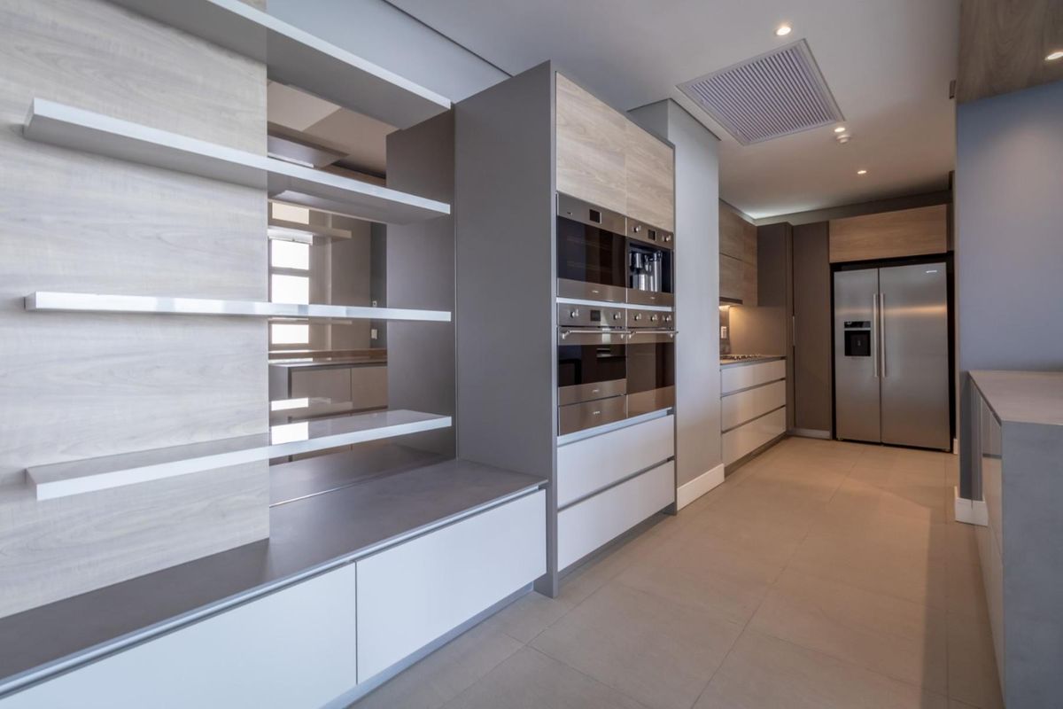 Modern kitchen featuring sleek cabinetry, integrated stainless steel appliances, built-in ovens, and recessed ceiling lighting with a clean, contemporary finish.