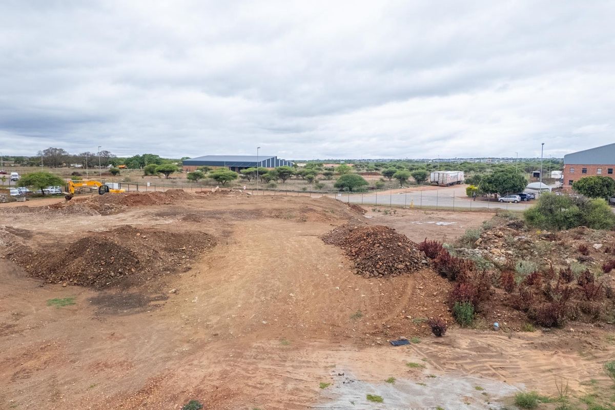 An elevated view of a vacant residential plot featuring cleared earth and surrounding landscape, suitable for future development.
