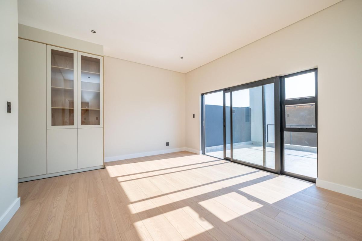 Bright and modern living area featuring light wood-look flooring, built-in cabinetry, and large sliding glass doors opening onto a private balcony.