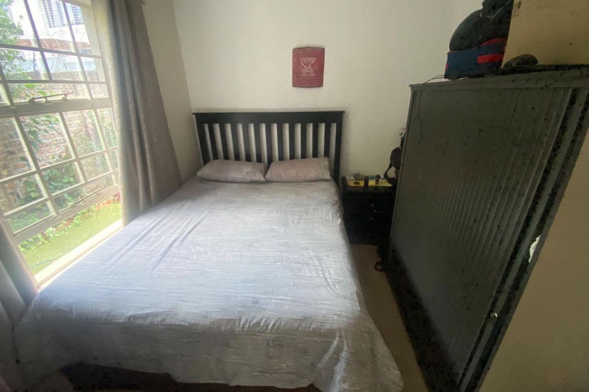 A compact bedroom featuring a window with natural light, neutral wall finishes, and space for a double bed.