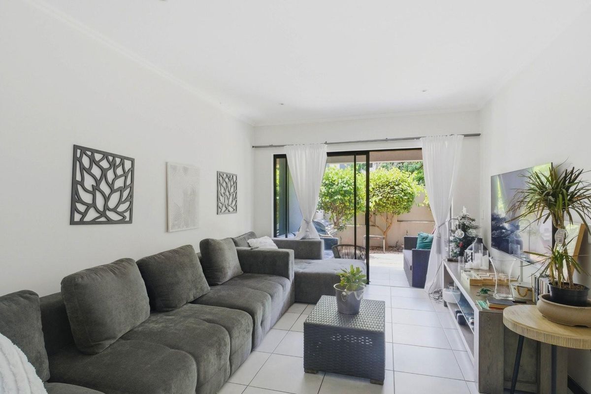 A bright living room featuring tiled flooring and large sliding glass doors that provide direct access to an outdoor patio area.