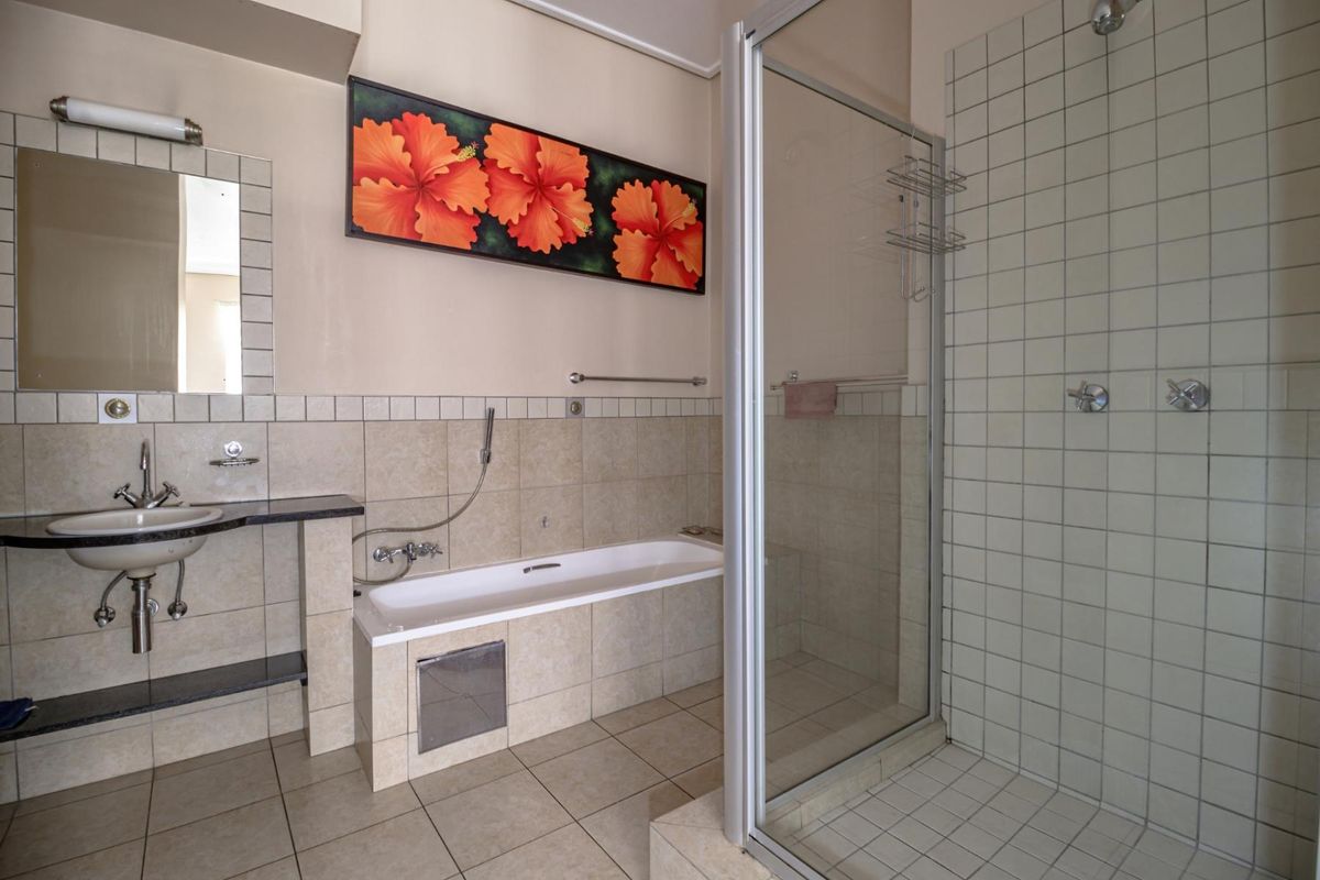 A functional bathroom featuring a separate shower enclosure, a built-in bathtub, and a vanity basin with tiled splashbacks.