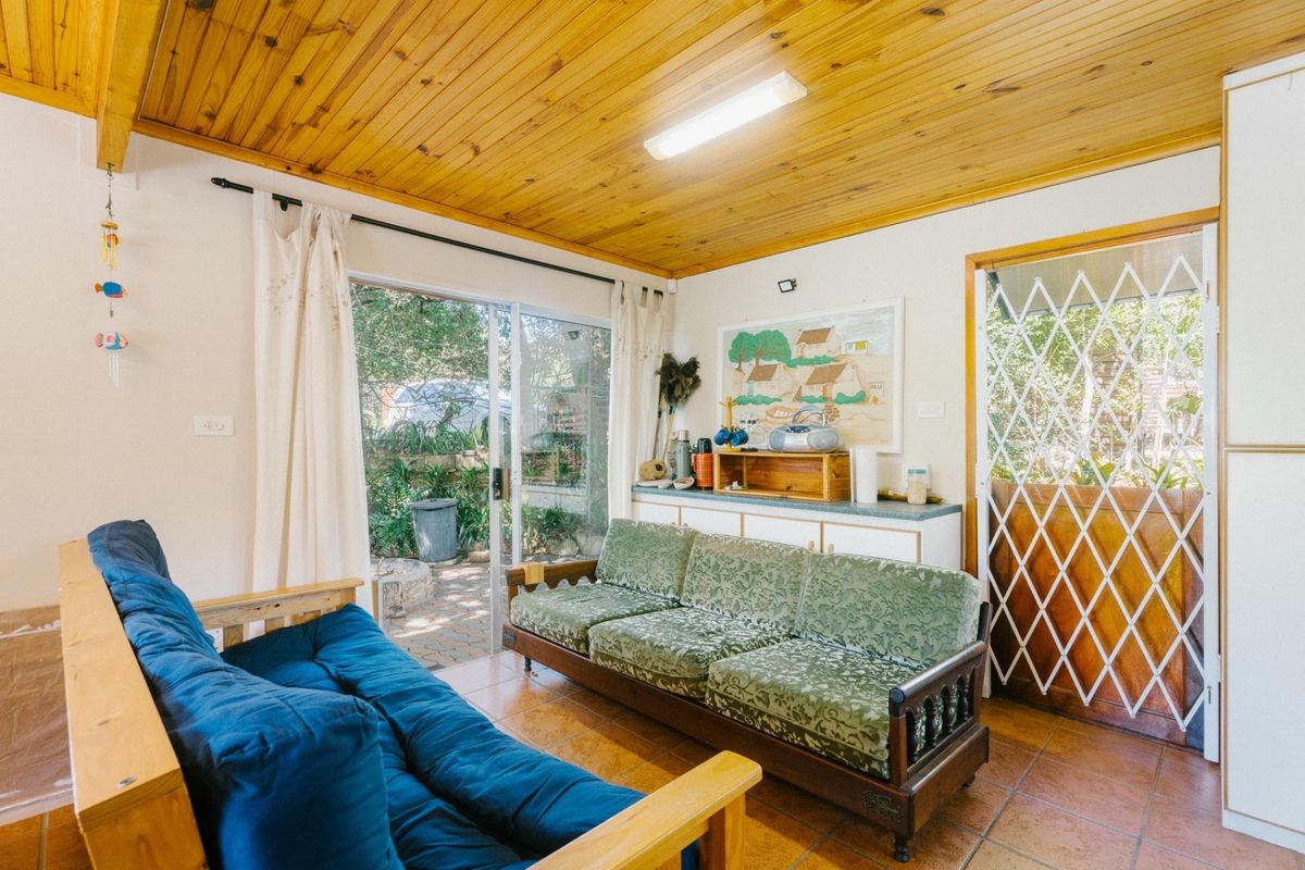 A living room featuring a timber-clad ceiling, tiled flooring, and sliding glass doors providing direct access to the outdoor patio area.