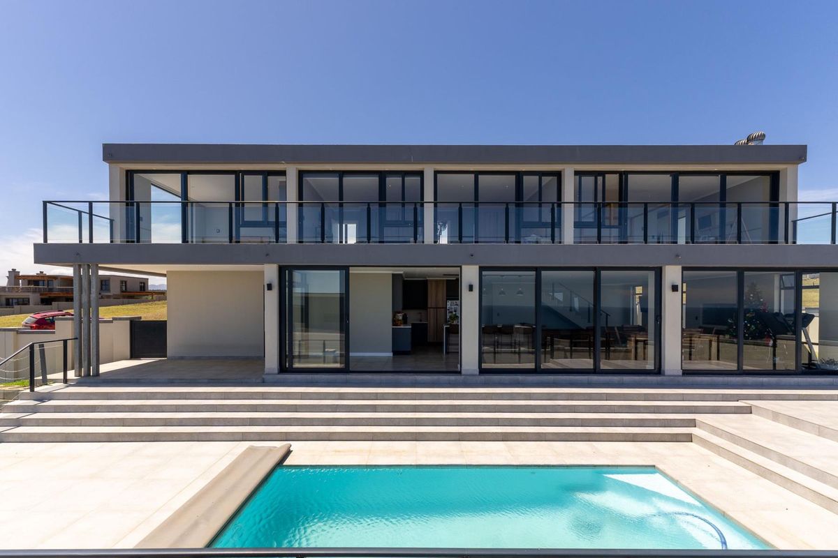 Modern two-story rear elevation featuring a swimming pool, expansive tiled patio, and large sliding glass doors leading to the interior living spaces.