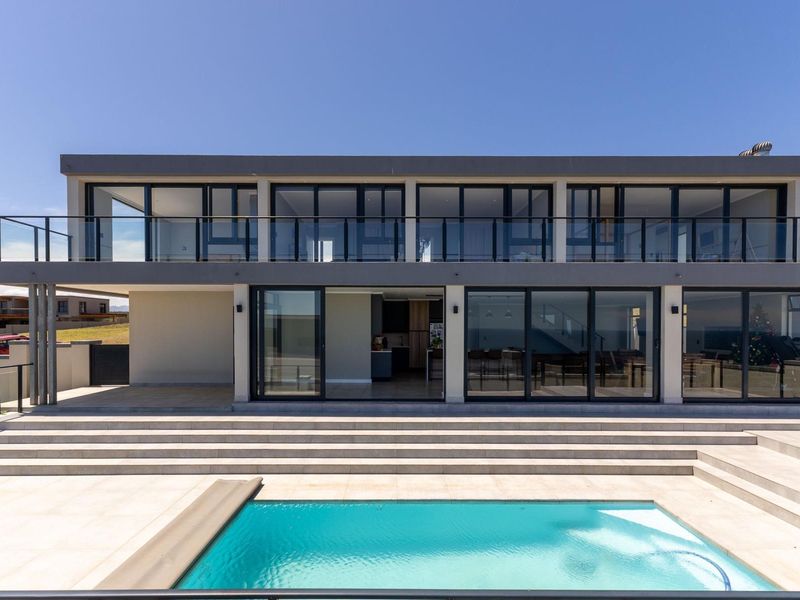 Modern two-story rear elevation featuring a swimming pool, expansive tiled patio, and large sliding glass doors leading to the interior living spaces.
