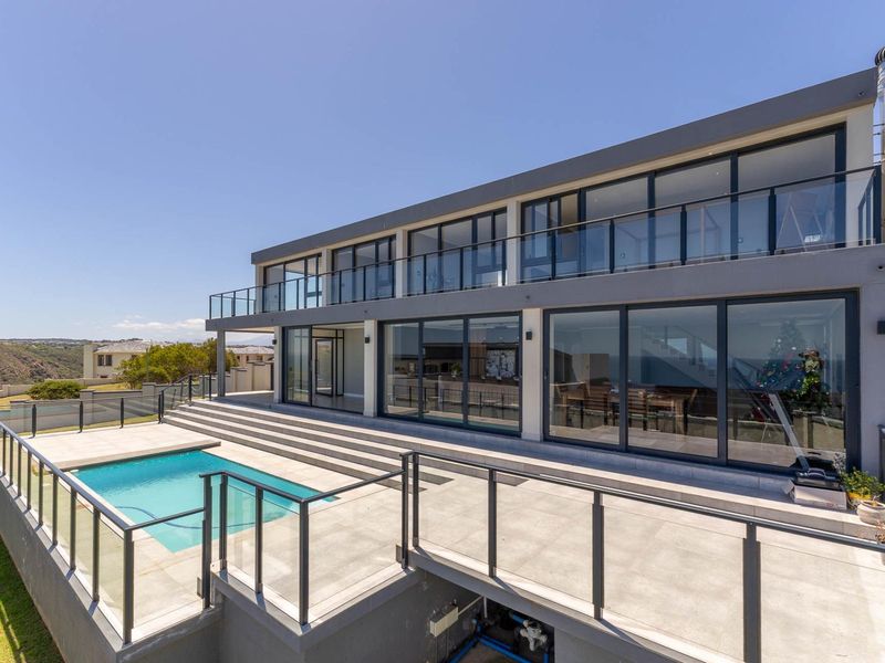 Modern rear elevation featuring a swimming pool, expansive tiled patio, and large sliding glass doors leading into the home.