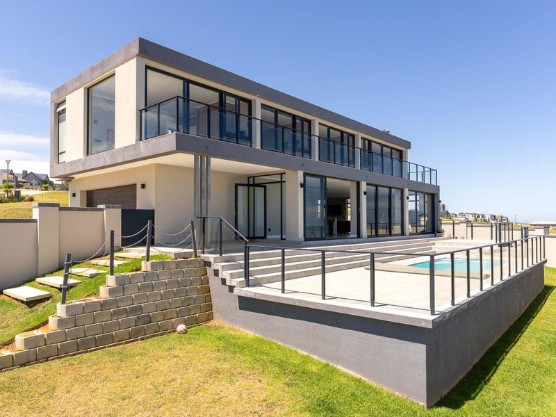 Modern double-story residence featuring a spacious rear terrace, swimming pool, glass balustrades, and extensive sliding glass doors for seamless indoor-outdoor living.