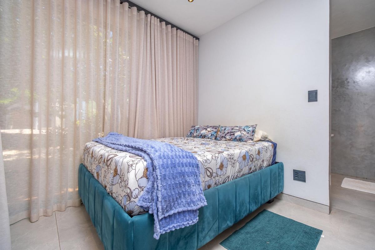 A modern bedroom featuring large floor-to-ceiling curtains, neutral tiled flooring, and clean white walls, providing a bright and comfortable living space.